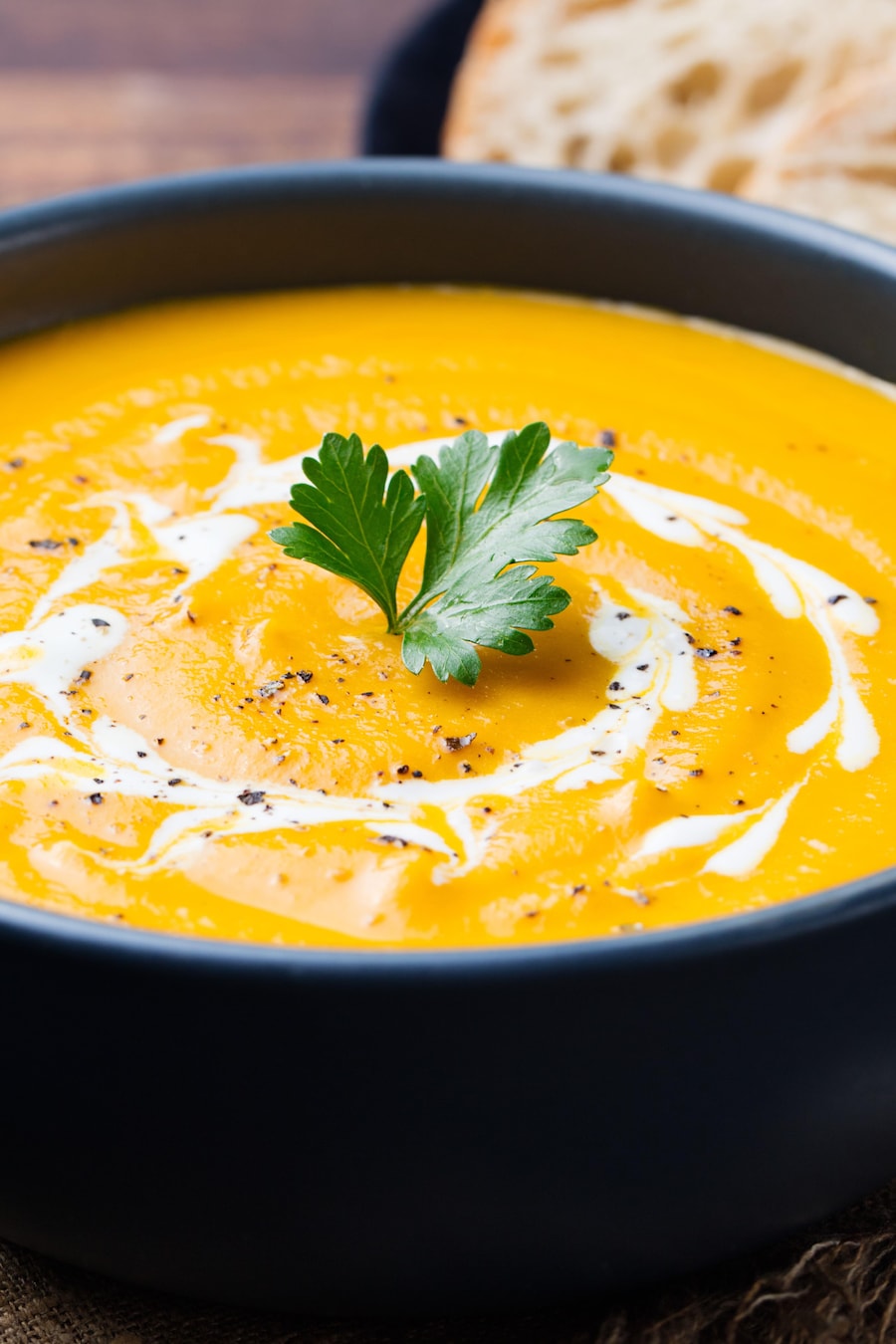 Une soupe de patates douces et de carottes avec un brin de coriandre sur le dessus.