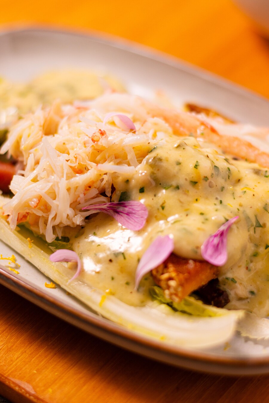 Une salade César au crabe recouverte de sauce dans une assiette.