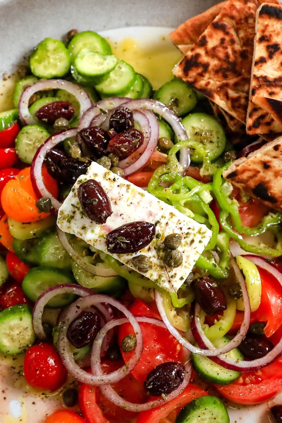 Une salade grecque composée d'olives, de tomates, de concombres et de poivrons, garnie de feta, d'olives et de câpres.