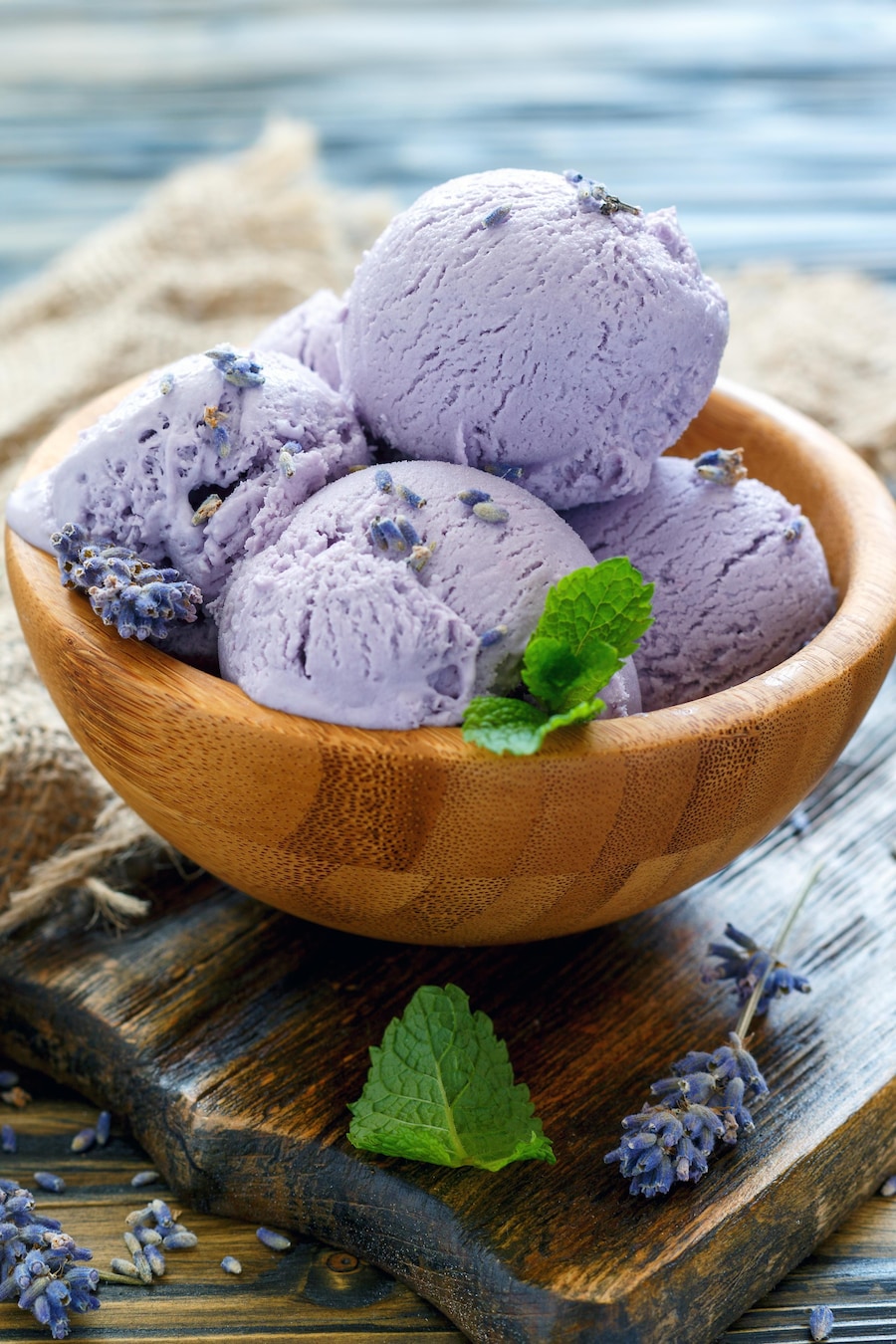 Un petit bol en bois rempli de plusieurs boules de crème glacée violettes à la lavande.