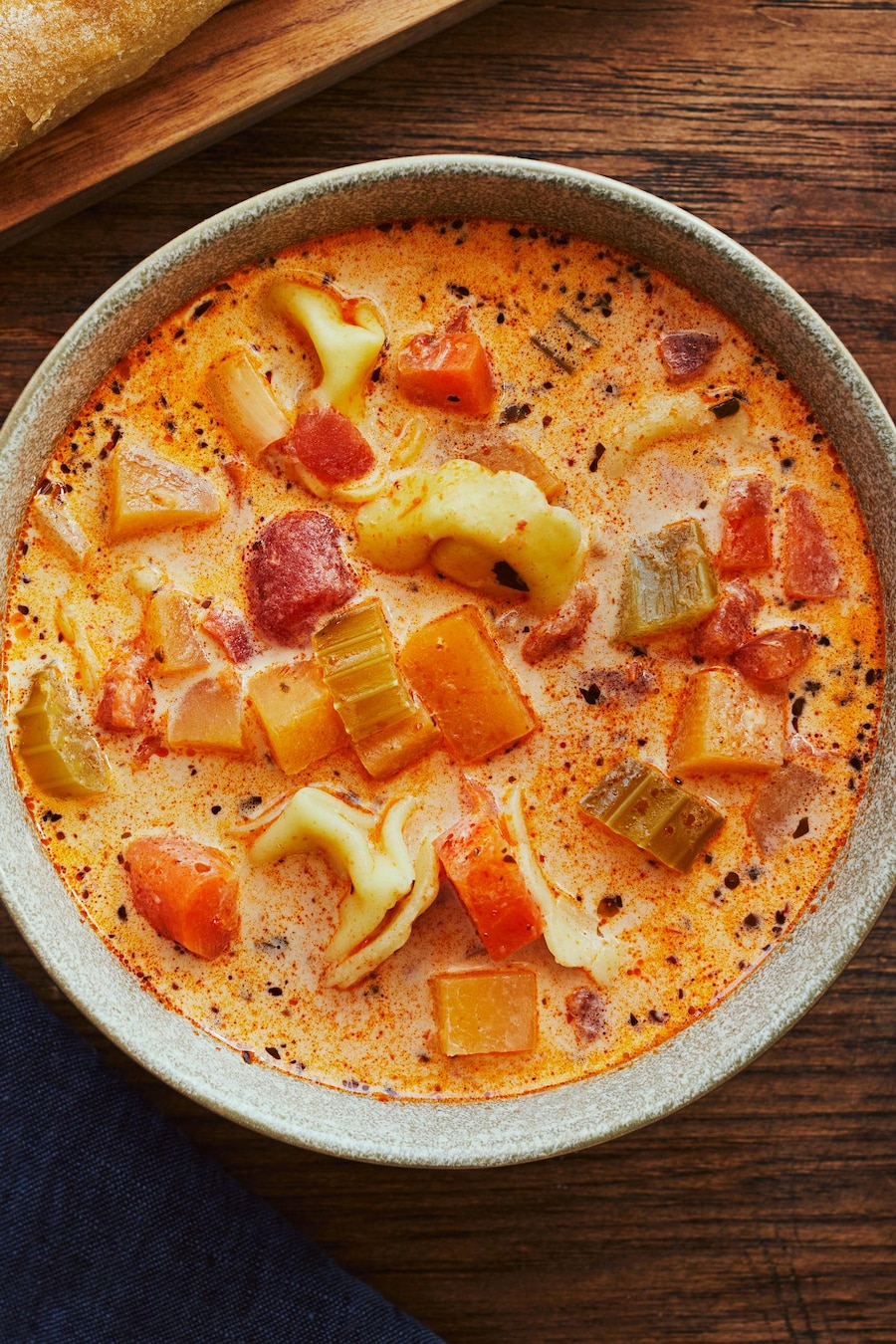 Un bol de soupe aux légumes et aux tortellinis sur un comptoir.