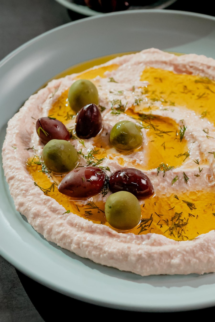 Une tartinade d’œufs de poisson dans une assiette recouverte d'olives et d'huile.