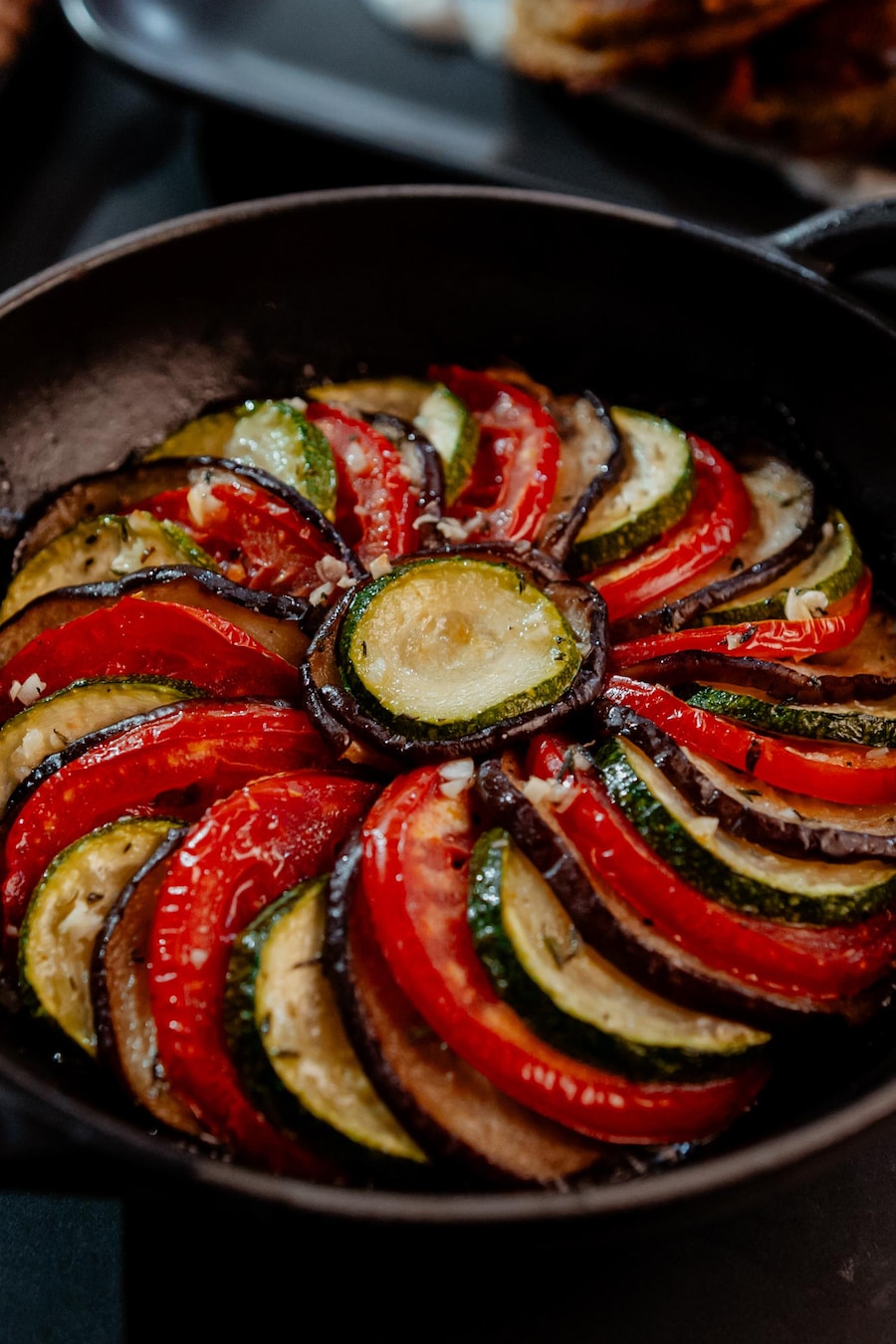 Des rondelles de légumes grillées superposées dans une casserole en fonte ronde. 