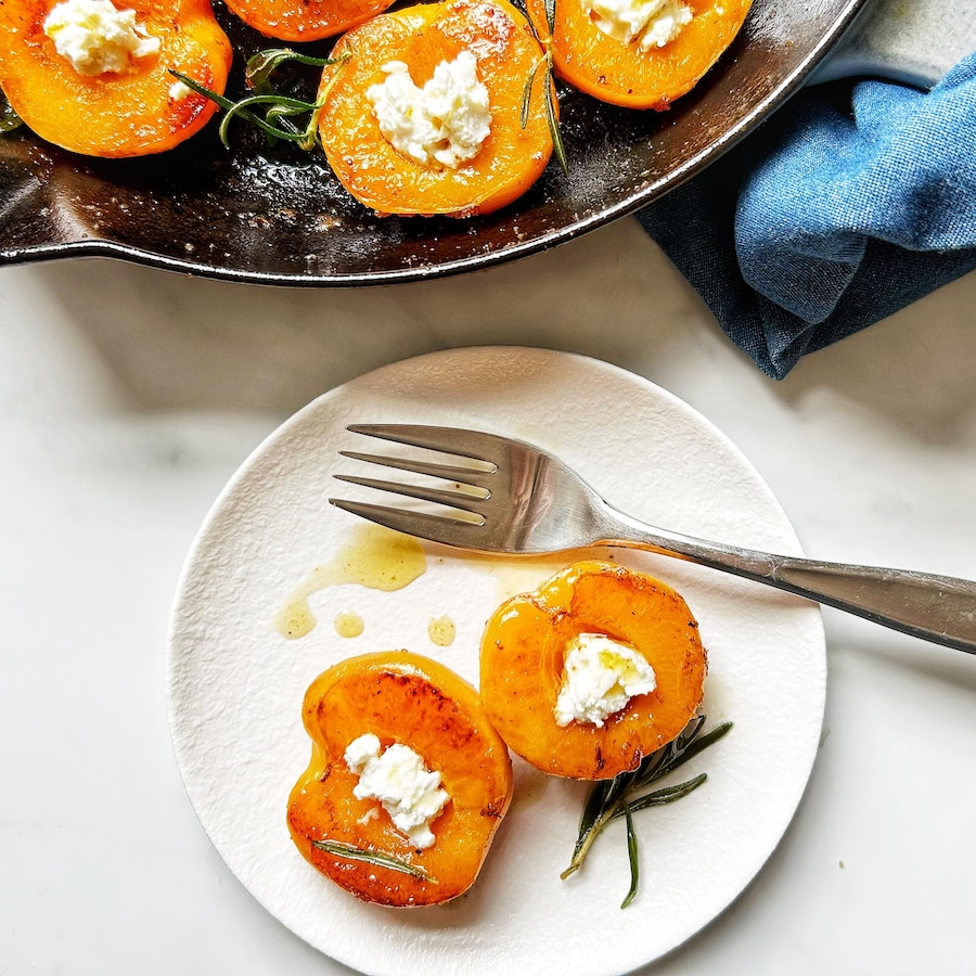 Des abricots caramélisés au fromage ricotta et au romarin dans une assiette.