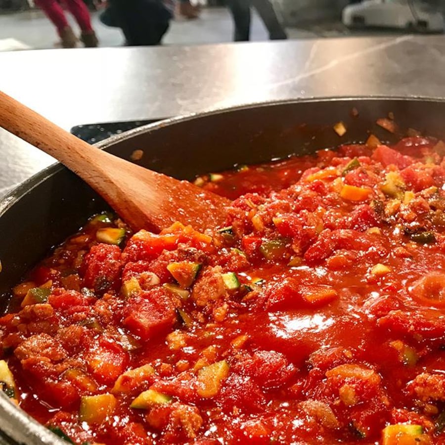 Une poêle remplie de sauce tomate avec une cuillère en bois.