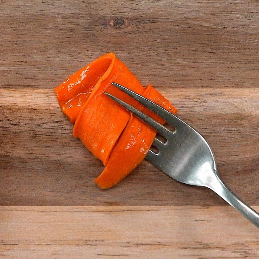 Une tranche de carotte confite enroulée sur une fourchette.