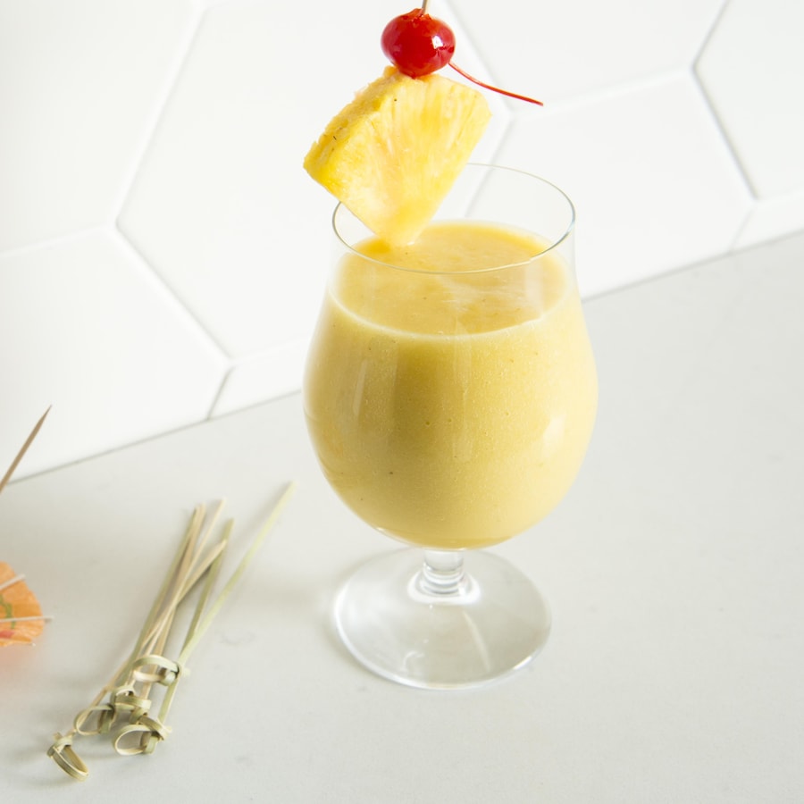 Le verre de pina colada est garni d'un morceau d'ananas et d'une cerise.