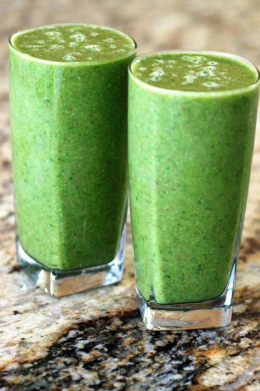 Deux grands verres de smoothie vert.
