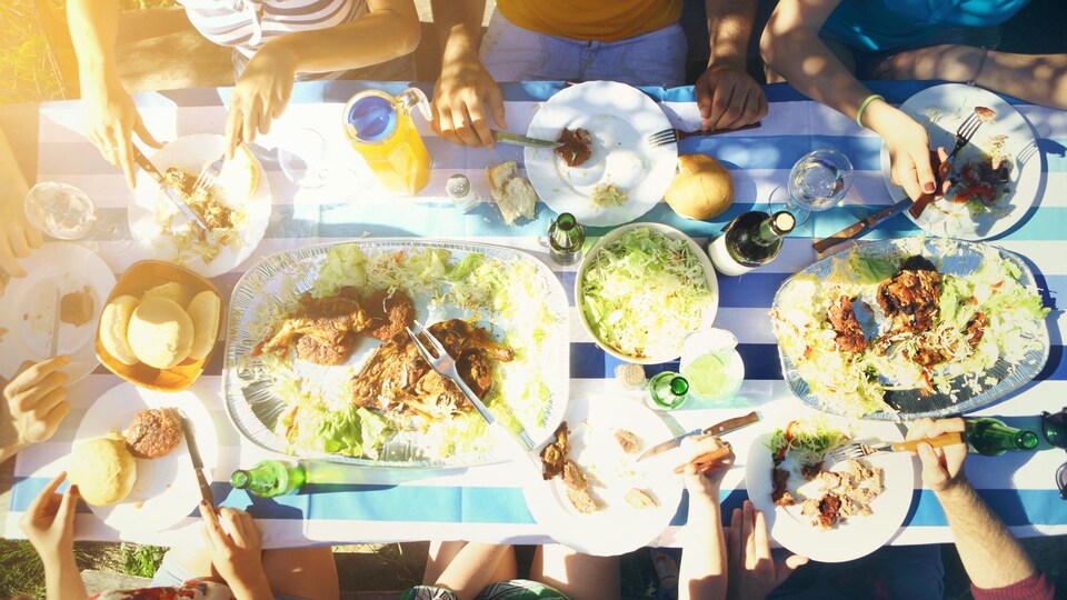 Un goupe de personnes est en train de manger à l'extérieur.