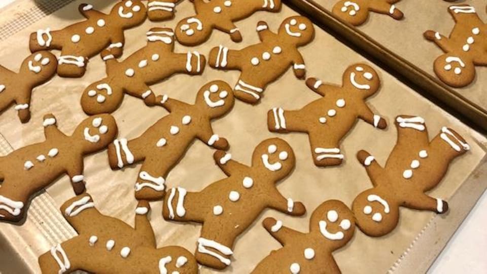 Des biscuits en forme de bonhomme décorés sur des plaques de cuisson.