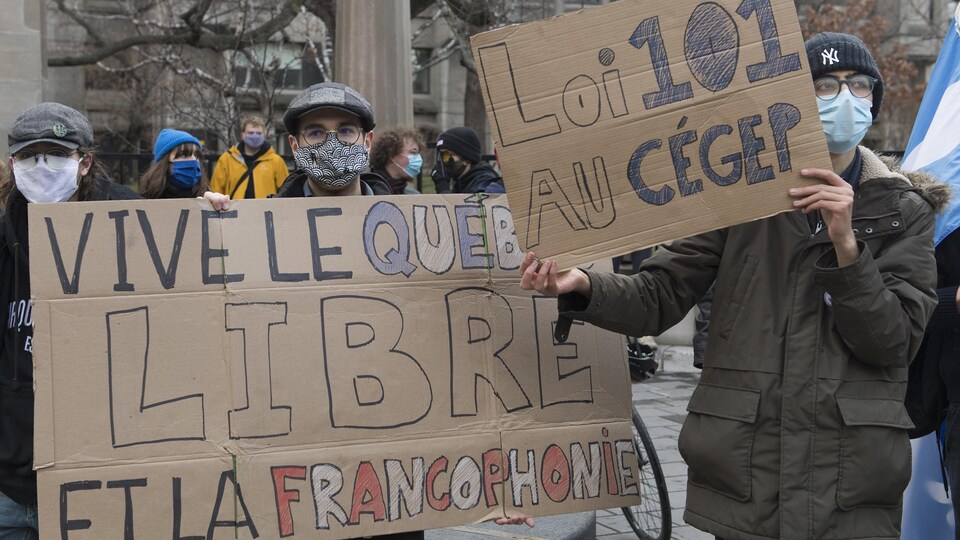 Des manifestants masqués, pendant la pandémie de COVID-19, tiennent des pancartes où sont écrits : "Vive le Québec Livre et la francophonie" ainsi que "Loi 101 au Cégep".