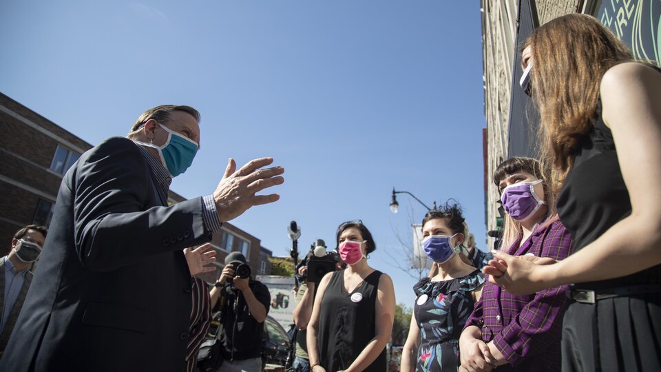 François Legault discute avec un groupe de femmes, tout le monde est masqué.