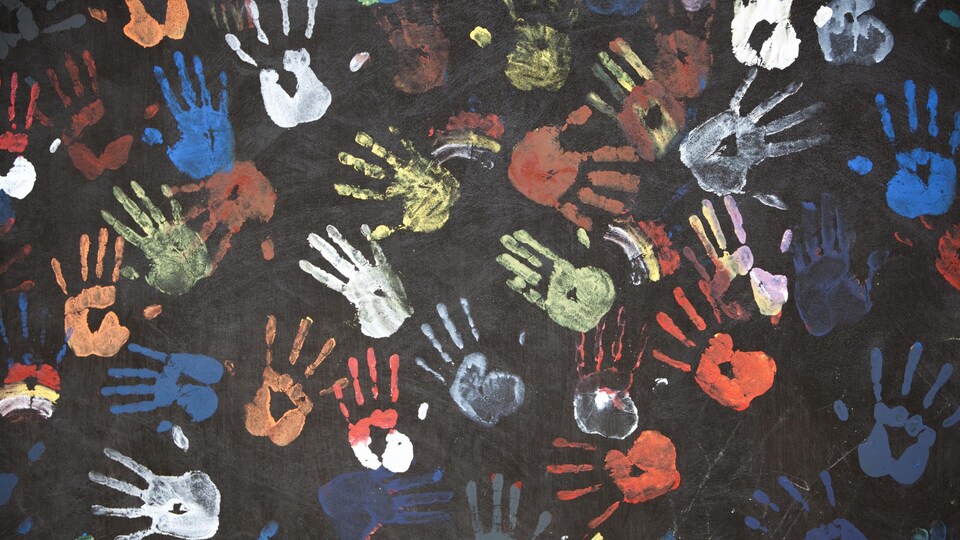 Des empreintes de mains colorées sur un tableau d'école