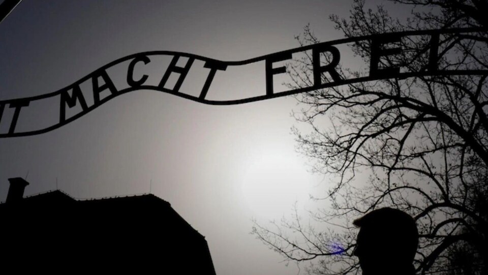Vue d'une silhouette passant devant le portail de l'ancien camp de concentration nazi.