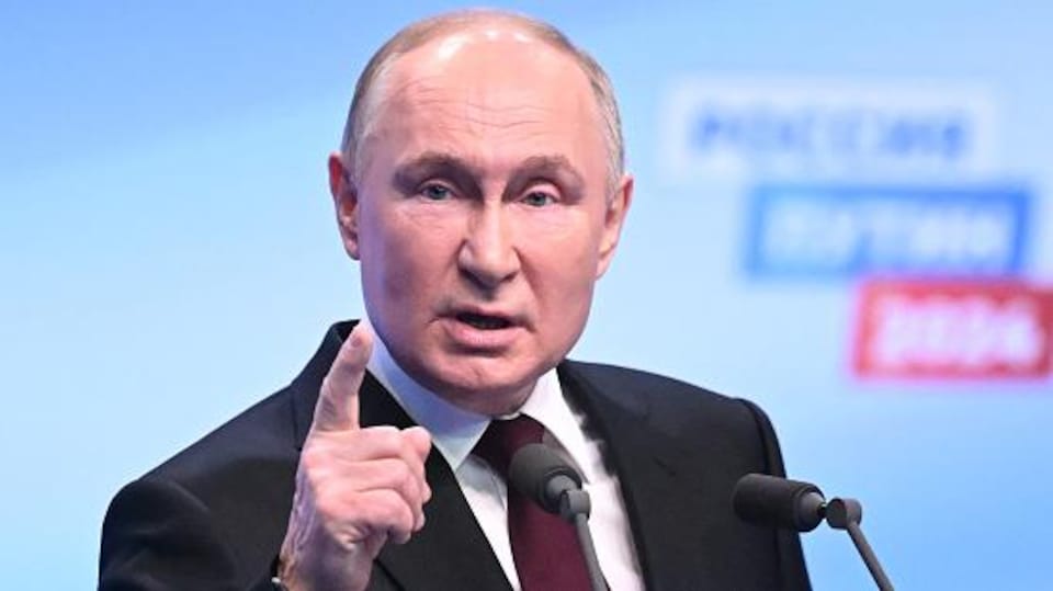 Vladimir Poutine parle devant les médias, le doigt pointé vers le haut, l'air sérieux.
