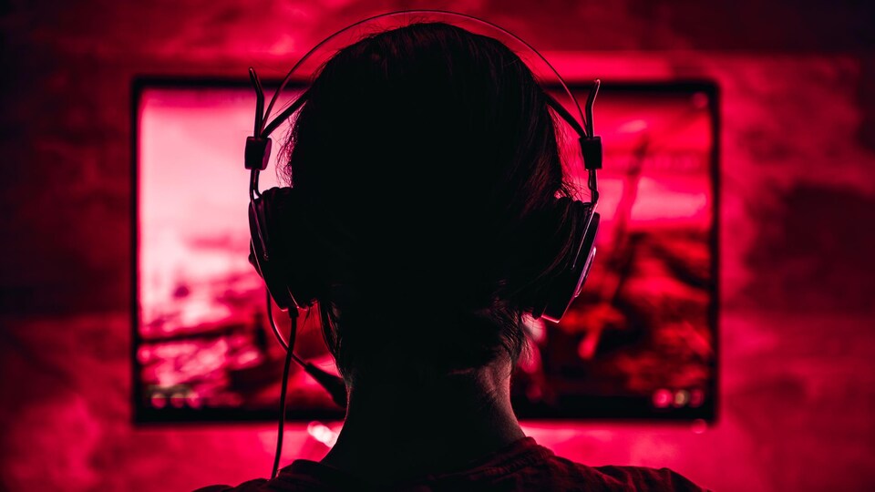 Une personne portant un casque d'écoute joue à un jeu vidéo. 