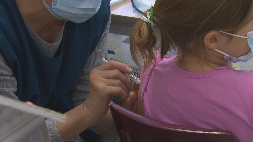Une infirmière vaccine une fillette.