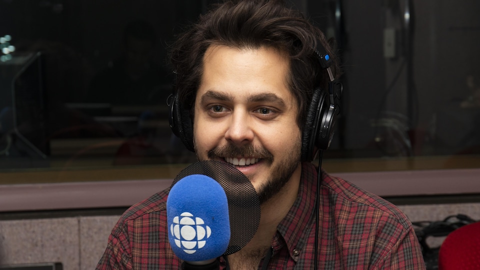 Matt Holubowski assis devant un micro radio.