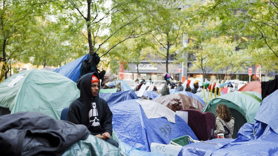 Un homme assied et entouré de tentes dans le parc Zuccotti à New York, lors d'Occupy Wall Street