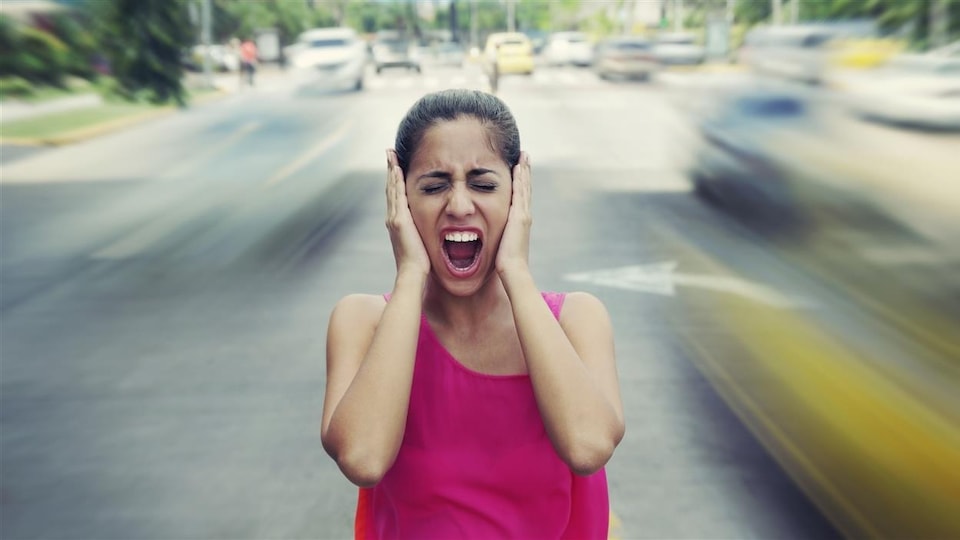 Une femme se bouche les oreilles à cause du bruit de la circulation