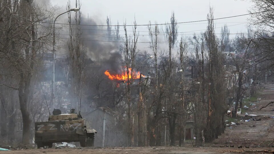 Un tank sur une route désolée avec un feu au loin.