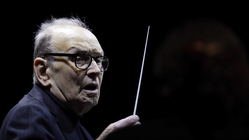 Ennio Morricone agite une baguette de maestro.