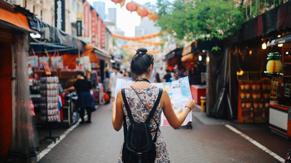 Une femme regarde une carte en se promenant dans la rue.
