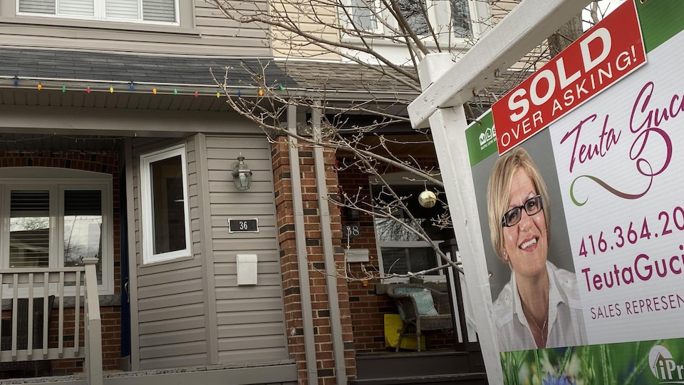 Une affiche disant « vendue au-dessus du prix demandé » devant une maison à Toronto.