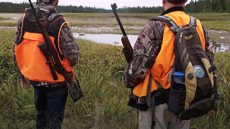 Deux chasseurs guettent l'horizon dans une clairière.