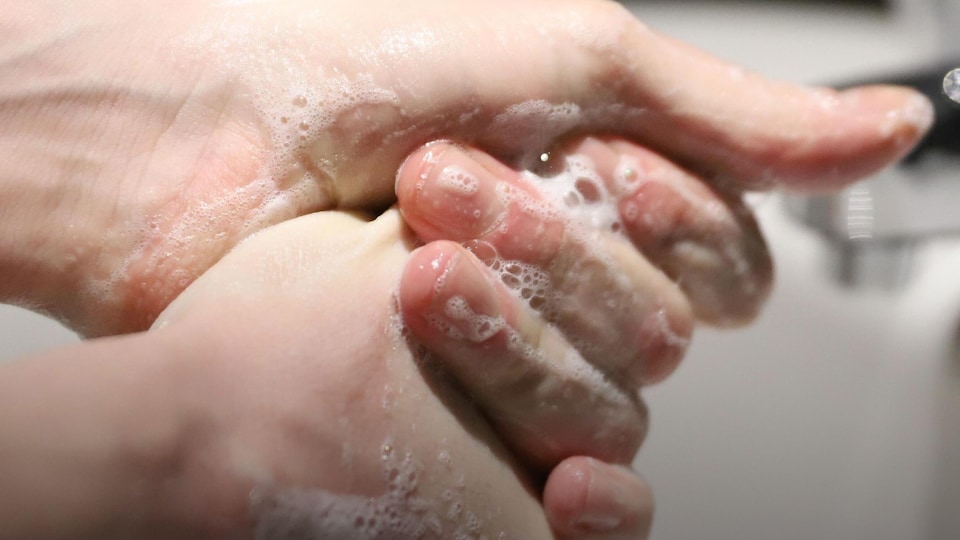 Des mains savonneuses sous un robinet. 