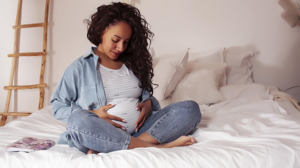 Une femme enceinte tient son ventre.