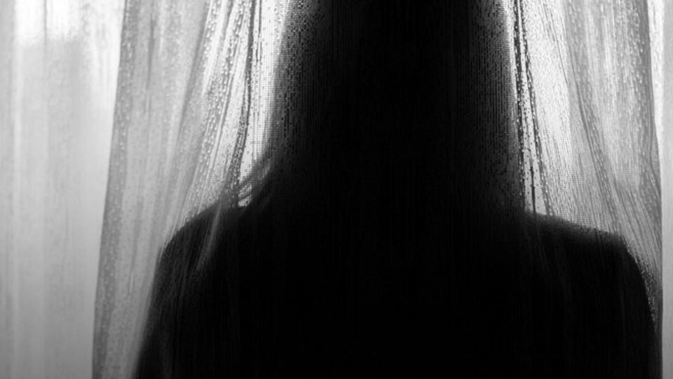 Une femme en contre jour de dos.
