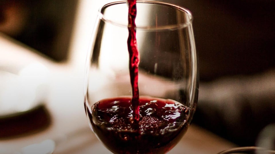 Du vin rouge est versé dans un verre.