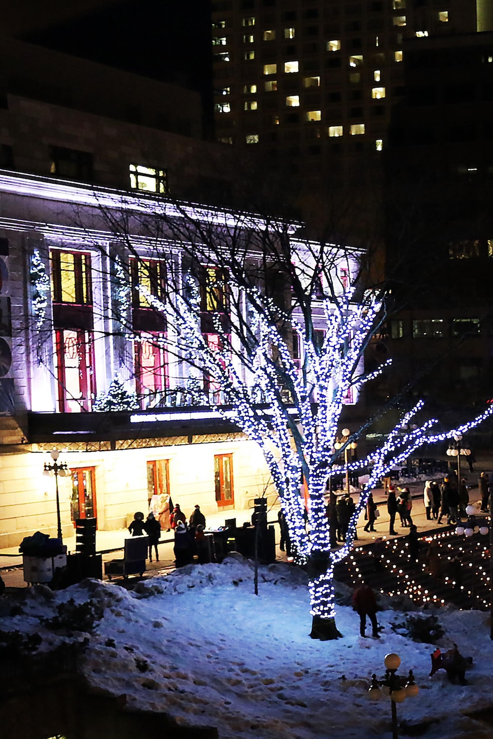Un bâtiment et une patinoire illuminés de lumières de Noël, le soir. 