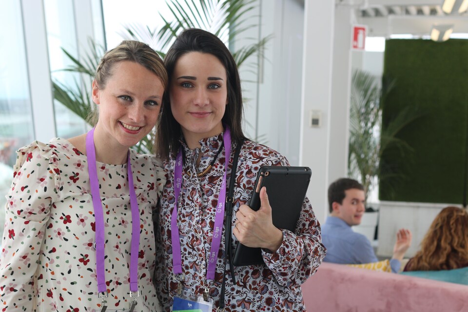 Deux jeunes femmes sourient à la caméra. 