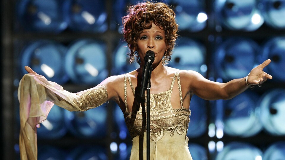 Whitney Houston chante sur une scène.
