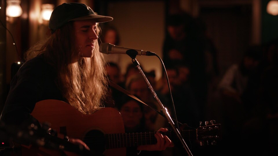 Le musicien Andy Shauf en performance avec une guitare et un micro.