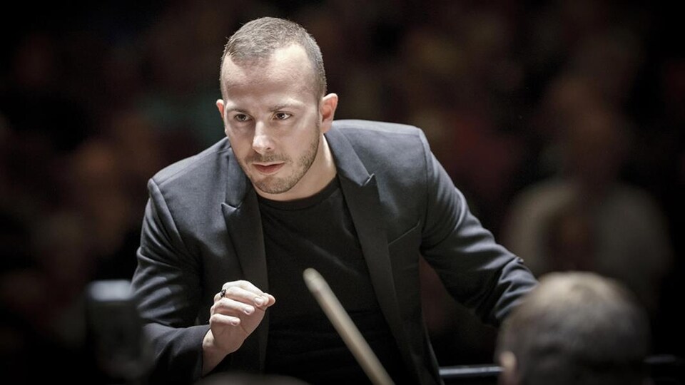 Le chef d'orchestre Yannick Nézet-Séguin, de face, attentif à son ensemble.
