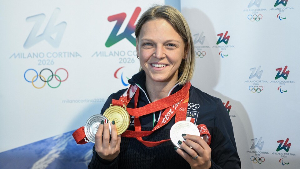Une patineuse montre ses médailles olympiques.