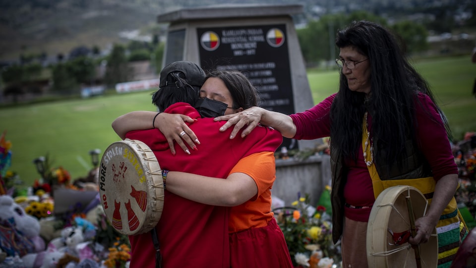 Katherine Cooper, de la Première Nation crie Mosakahiken, au Manitoba, console une amie devant un monument à la mémoire des enfants autochtones enterrés à Kamloops.