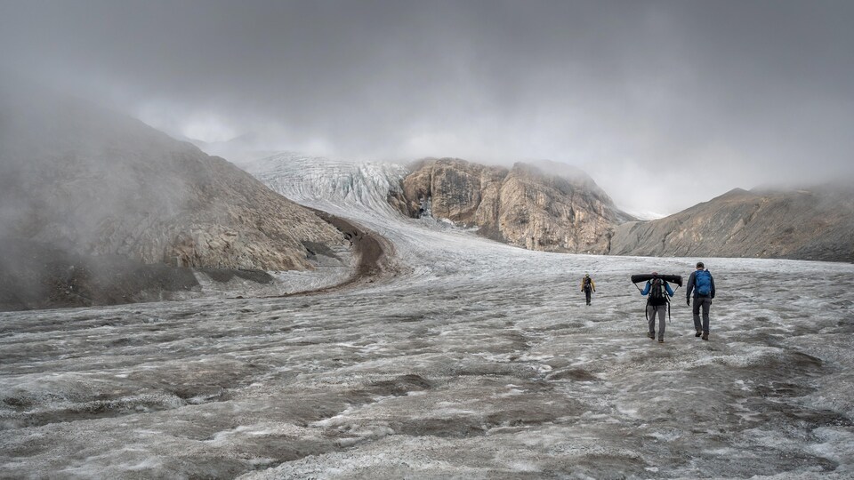 Des hommes marchent sur un glacier.