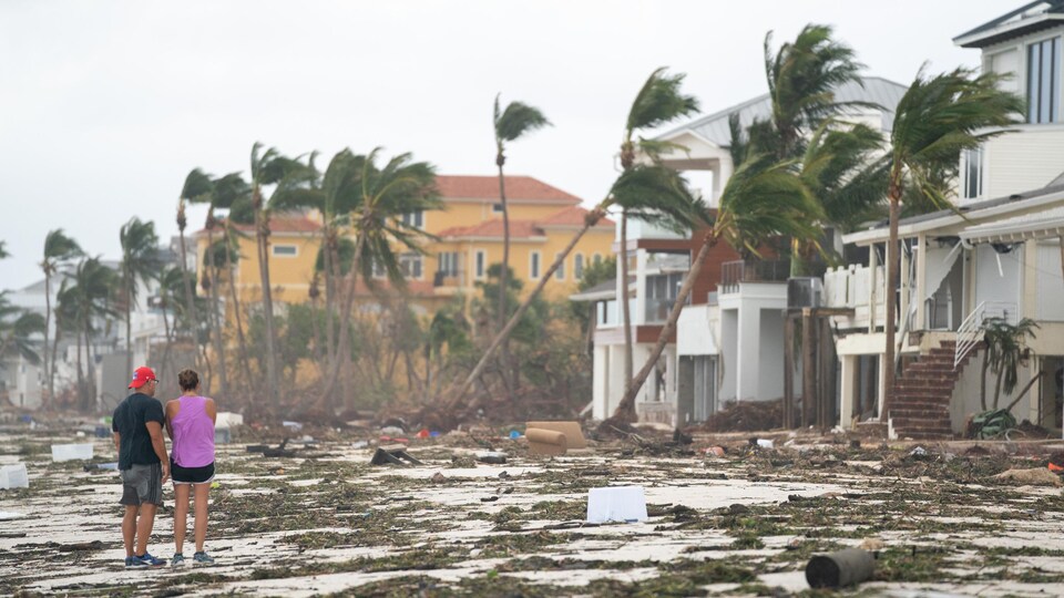Des personnes marchent le long de la plage en regardant les biens endommagés par l'ouragan Ian à Bonita Springs.