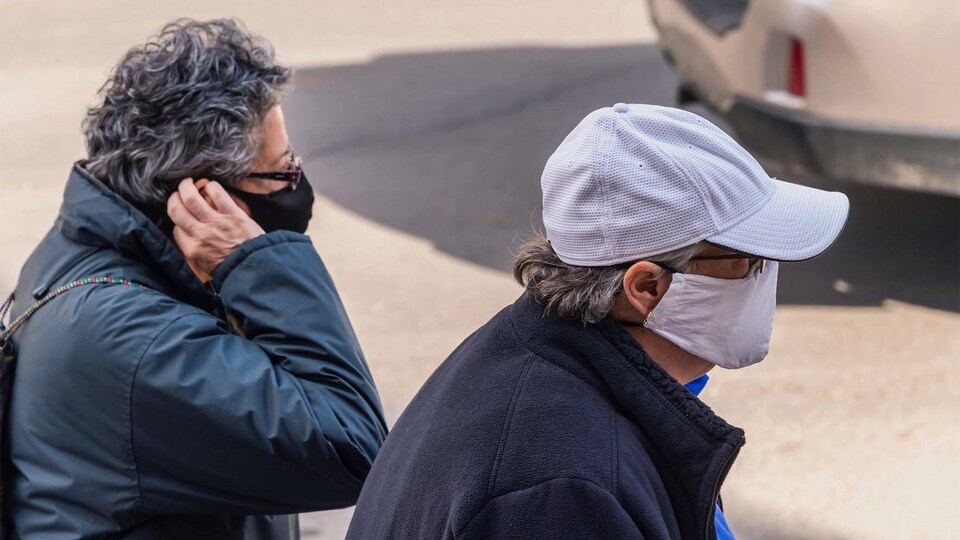 Deux personnes marchent dans la rue, elles portent un masque de protection contre la covid-19.
