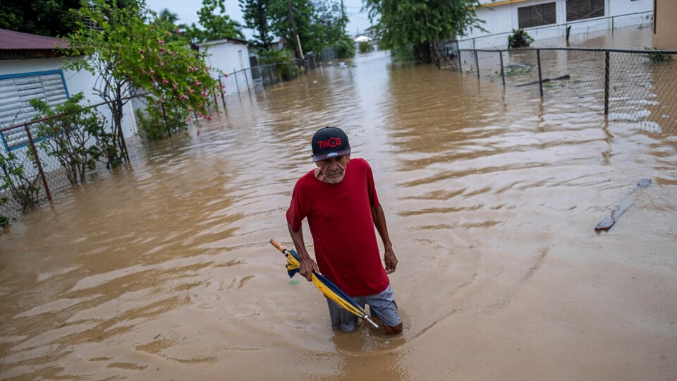 Un homme circule sur une route inondée.