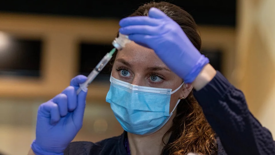 Une femme rempli une seringue avec le vaccin contre la COVID-19.