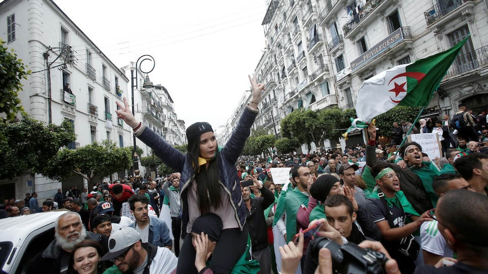 Un homme porte une femme sur ses épaules à Alger lors du 11e vendredi de manifestations contre ce qui reste du pouvoir de l’ancien président Abdelaziz Bouteflika.