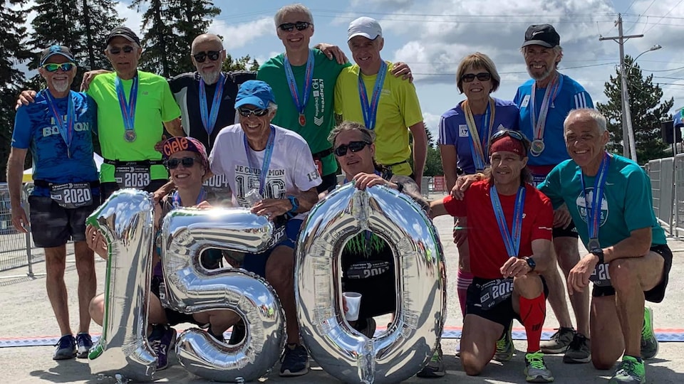 Une dizaine de personnes venant de terminer une course posent avec des ballons indiquant 150.