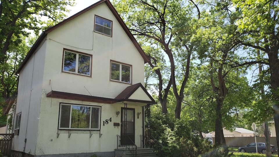 Une maison à deux étages entourée d'arbres.