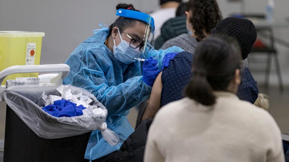 Une infirmière est en train d'administrer un vaccin contre la COVID-19.