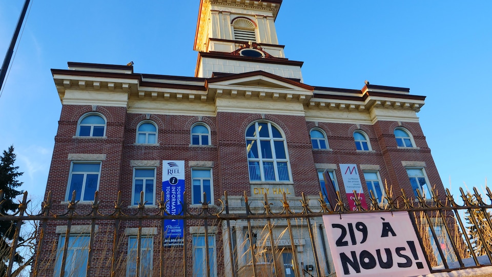 Une pancarte indiquant "219 à nous" est accrochée à une barrière devant l'ancienne mairie de Saint-Boniface.